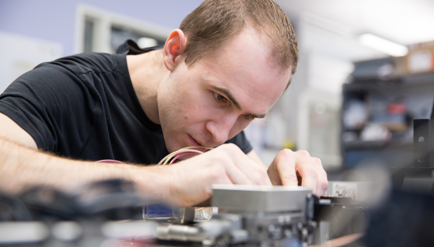 man works intently on a mechanical device at a lab bench