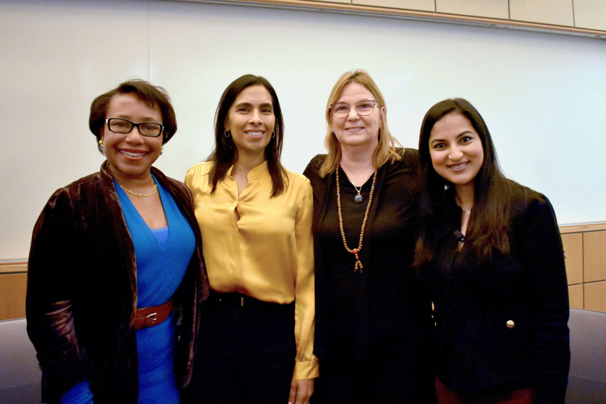 four women pose together with their arms around one another