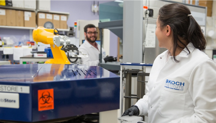 Two researchers working near a robotic arm