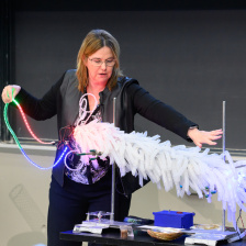 Angela Belcher demos a light-up model of M13 bacteriophage, a large tube covered in white plastic curlicues and fairy lights