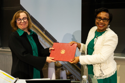 Two women both holding a red leather certificate folder